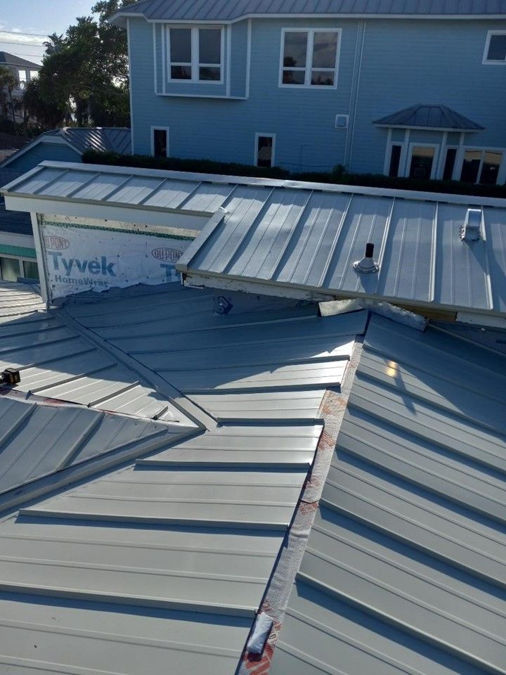 An aerial view of a roof with a blue house in the background — Tampa, FL — Bill Shields Roofing