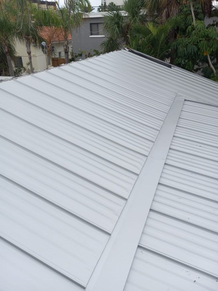 A white metal roof is sitting on top of a house — Tampa, FL — Bill Shields Roofing