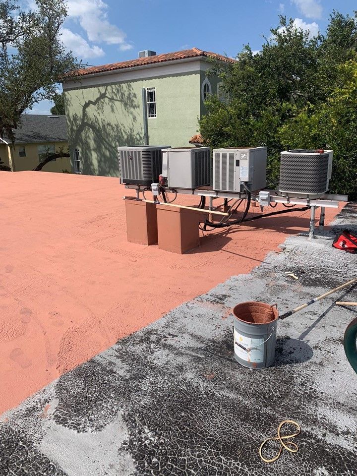 A roof with a lot of air conditioners on it and a green building in the background — Tampa, FL — Bill Shields Roofing