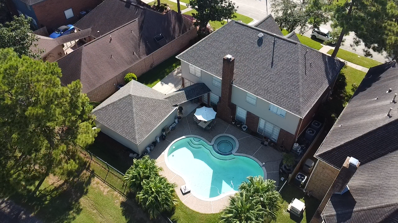 An aerial view of a house with a swimming pool in the backyard.