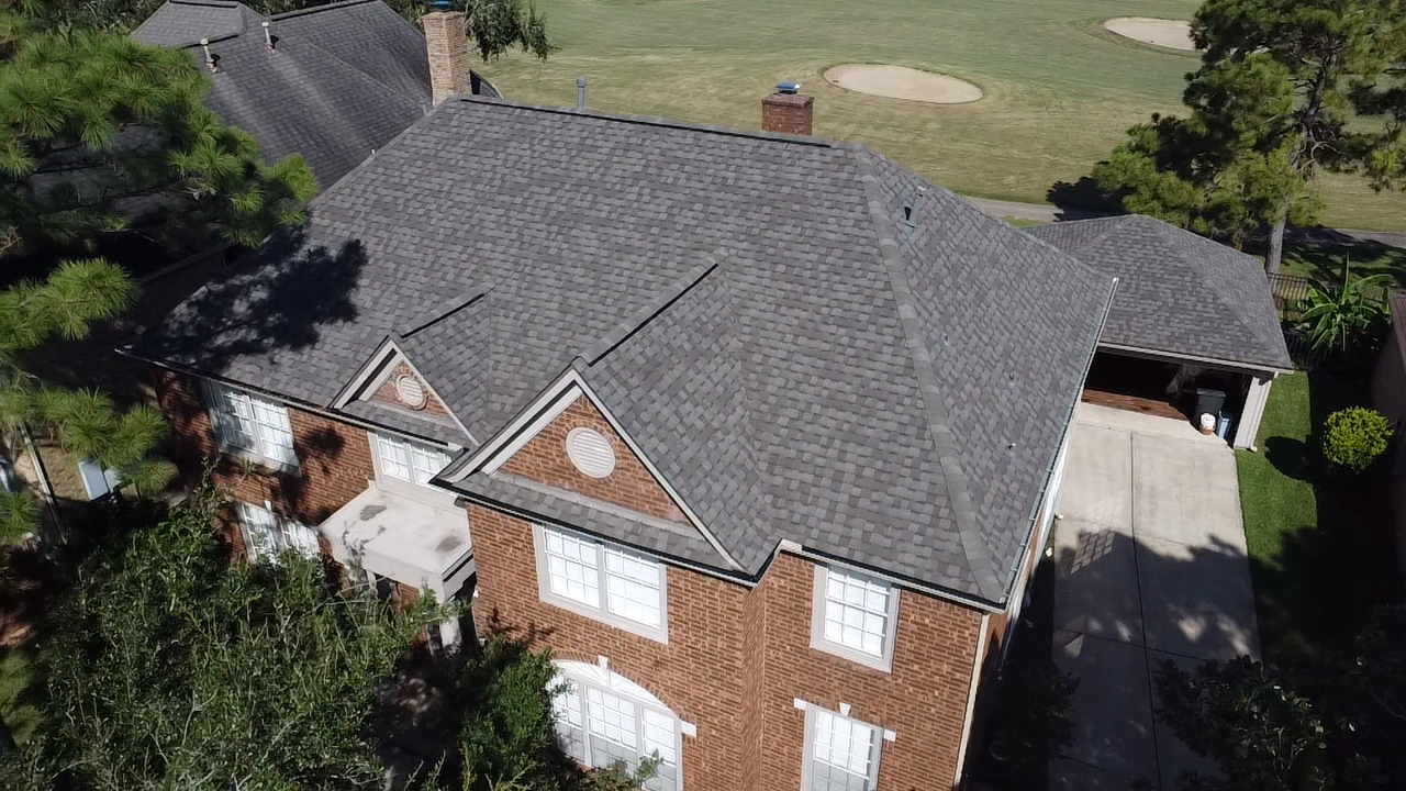 An aerial view of a large brick house with a gray roof.