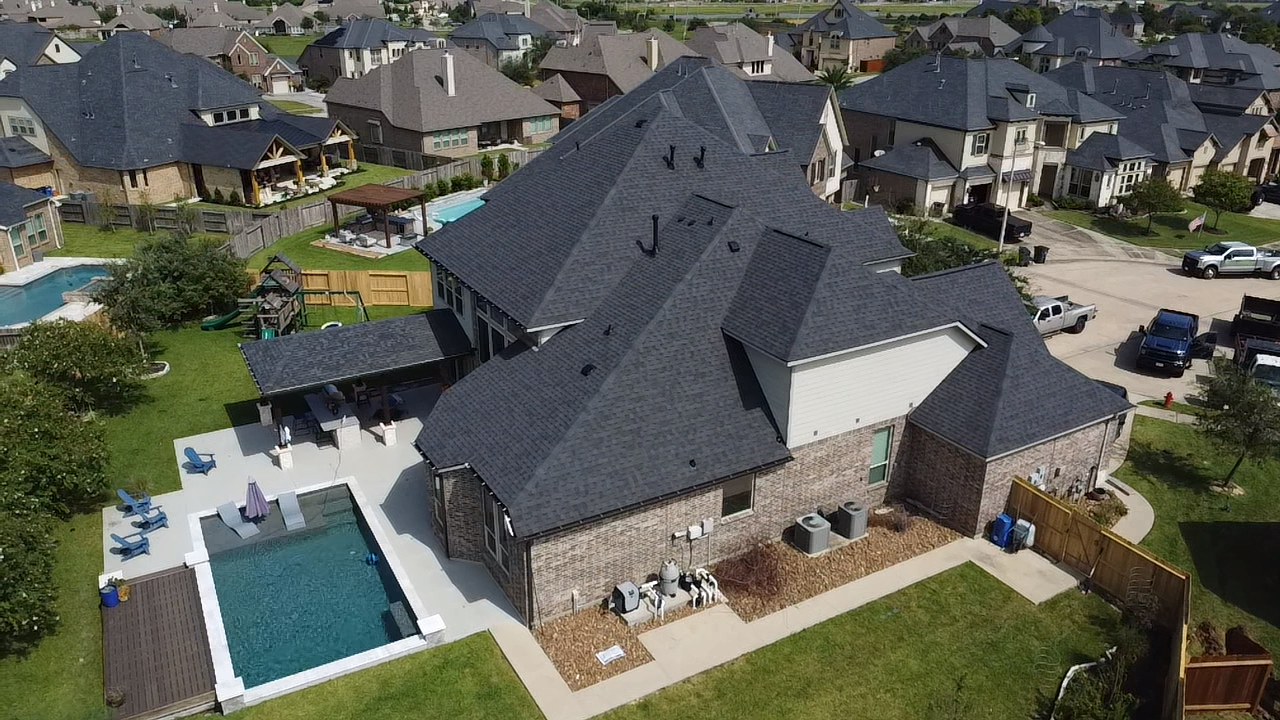 An aerial view of a large house with a pool in the backyard.