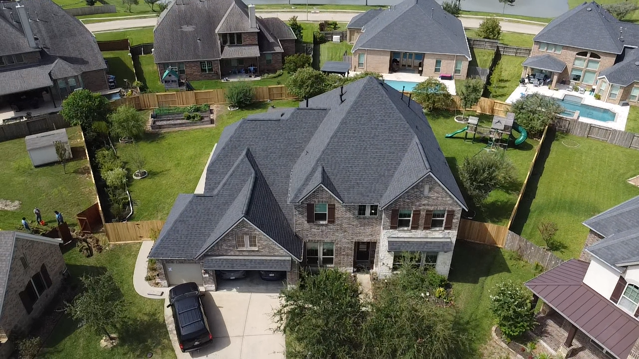 An aerial view of a house in a residential area with a car parked in front of it.