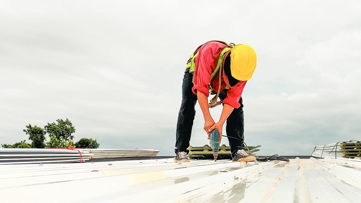 Roofing contractor uses an electric screw gun to install roofing.