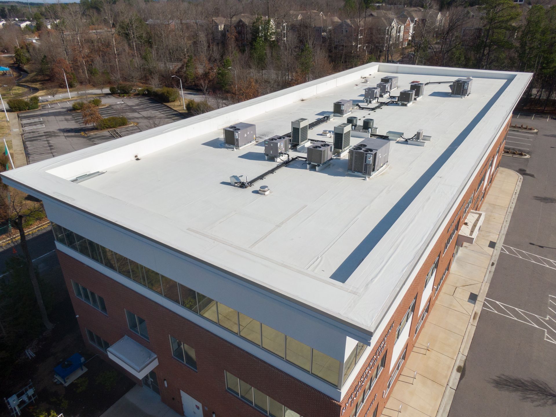 Aerial view of a flat commercial roof with HVAC units on a large brick building.