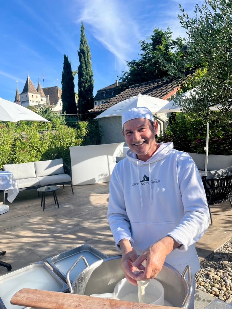 Un homme portant un chapeau de chef se tient devant une grande marmite.