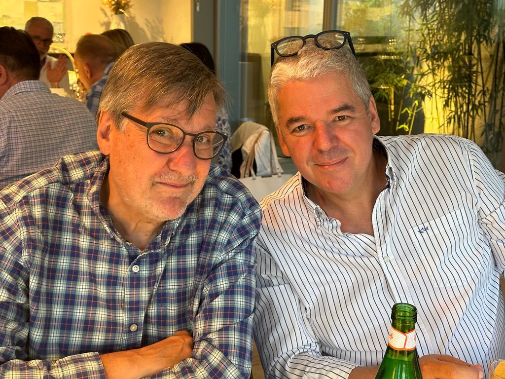 Deux hommes sont assis à une table avec une bouteille de bière.