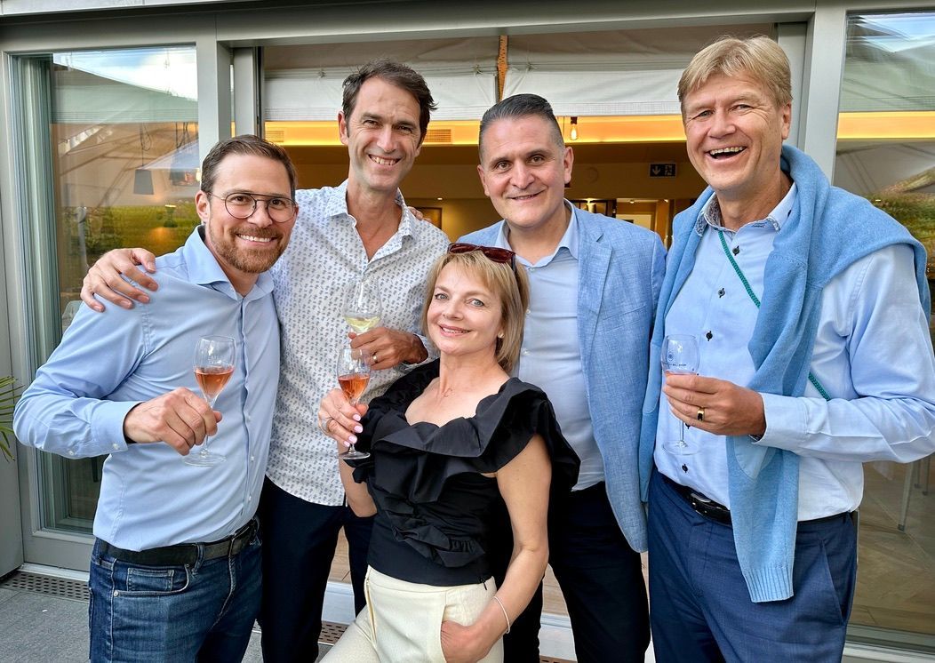 Un groupe de personnes pose pour une photo tout en tenant des verres à vin.