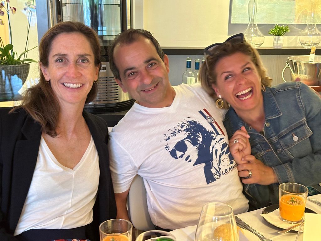 Un homme et deux femmes posent pour une photo assis à une table.