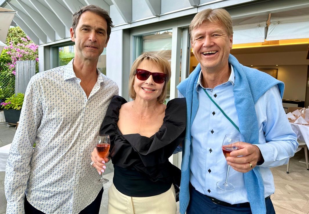 Deux hommes et une femme posent pour une photo tout en tenant des verres à vin.