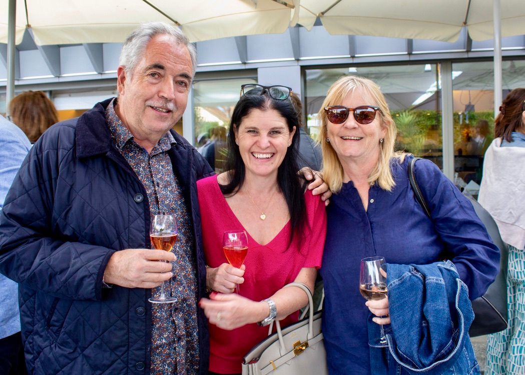 Un homme et deux femmes posent pour une photo tout en tenant des verres à vin.