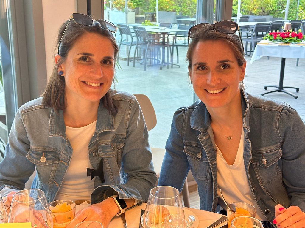 Deux femmes sont assises à une table avec des verres de vin.