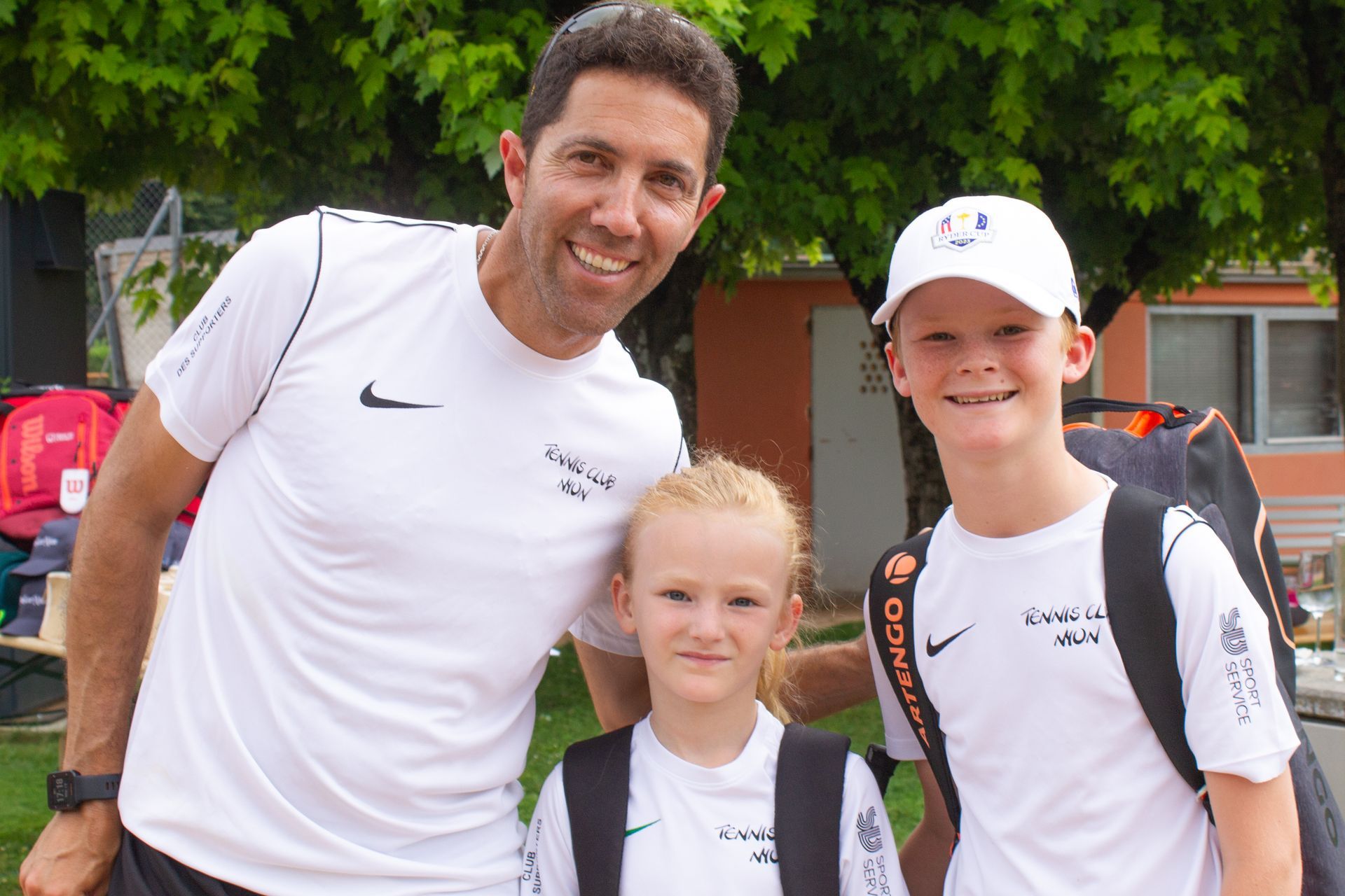 Un homme et deux enfants posent pour une photo et l'homme porte un t-shirt Nike