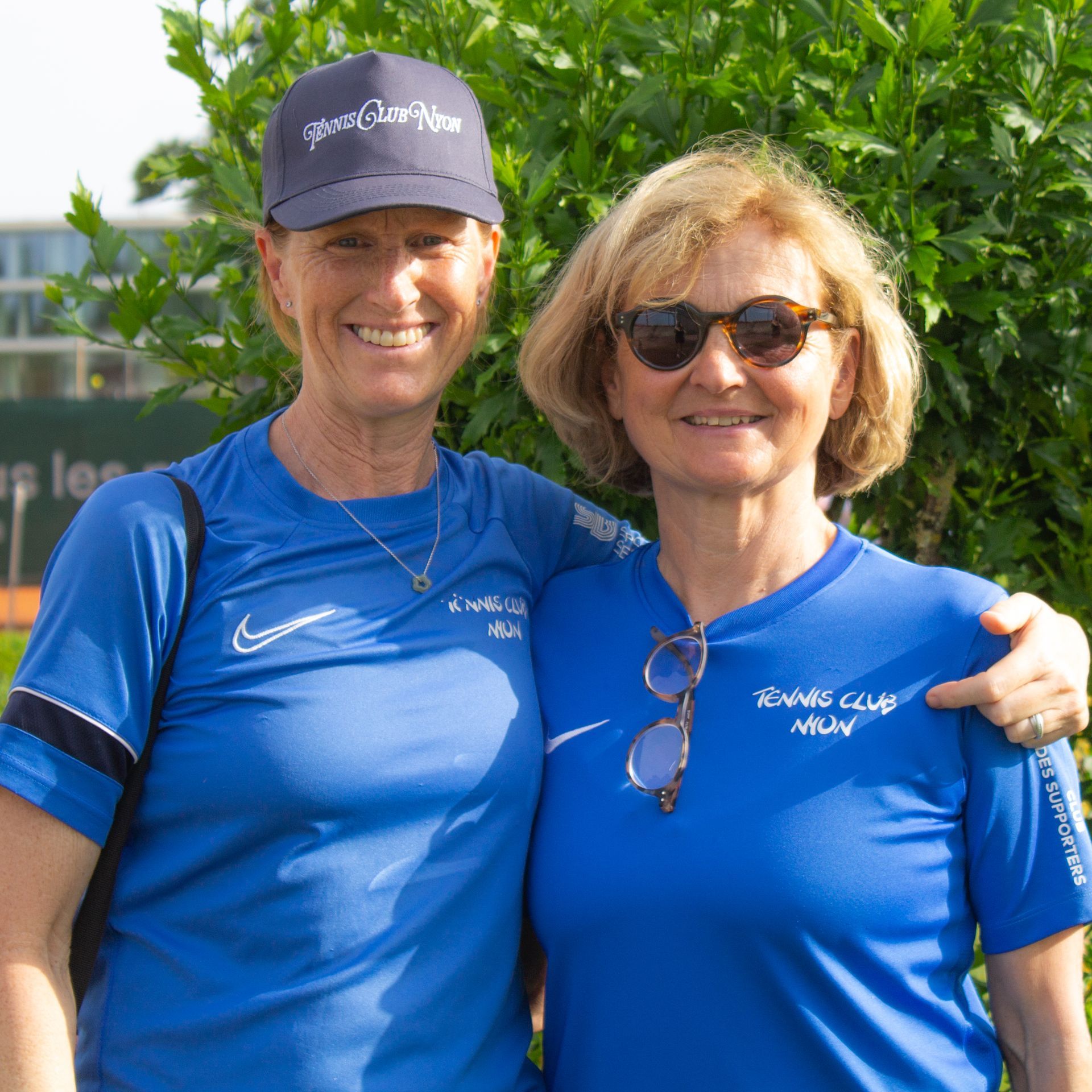 Deux femmes portant des chemises bleues du club de tennis posent pour une photo