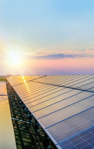 Une rangée de panneaux solaires au sommet d'un bâtiment avec le soleil qui brille à travers eux.