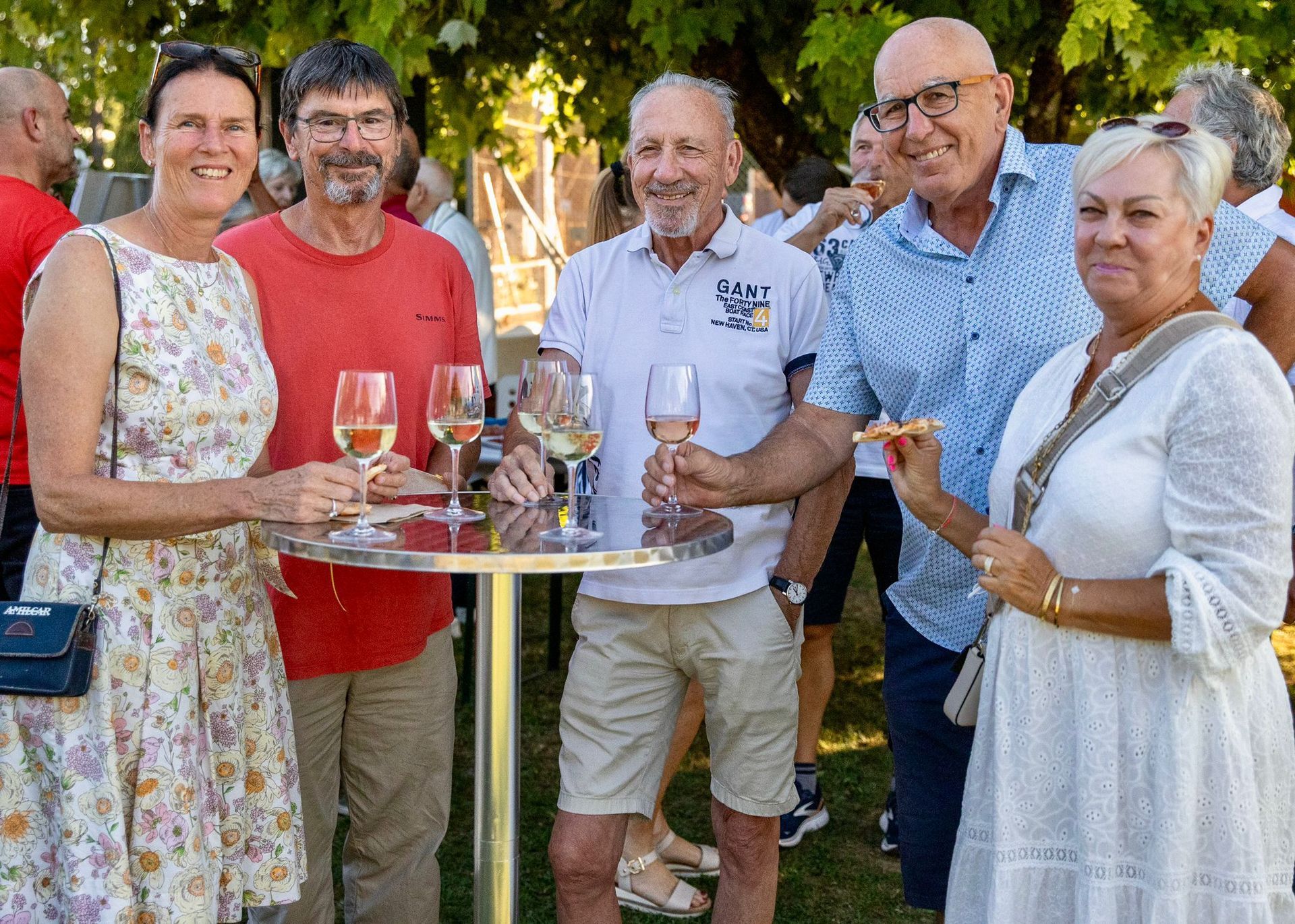 Un groupe de personnes se tient autour d'une table tenant des verres à vin.