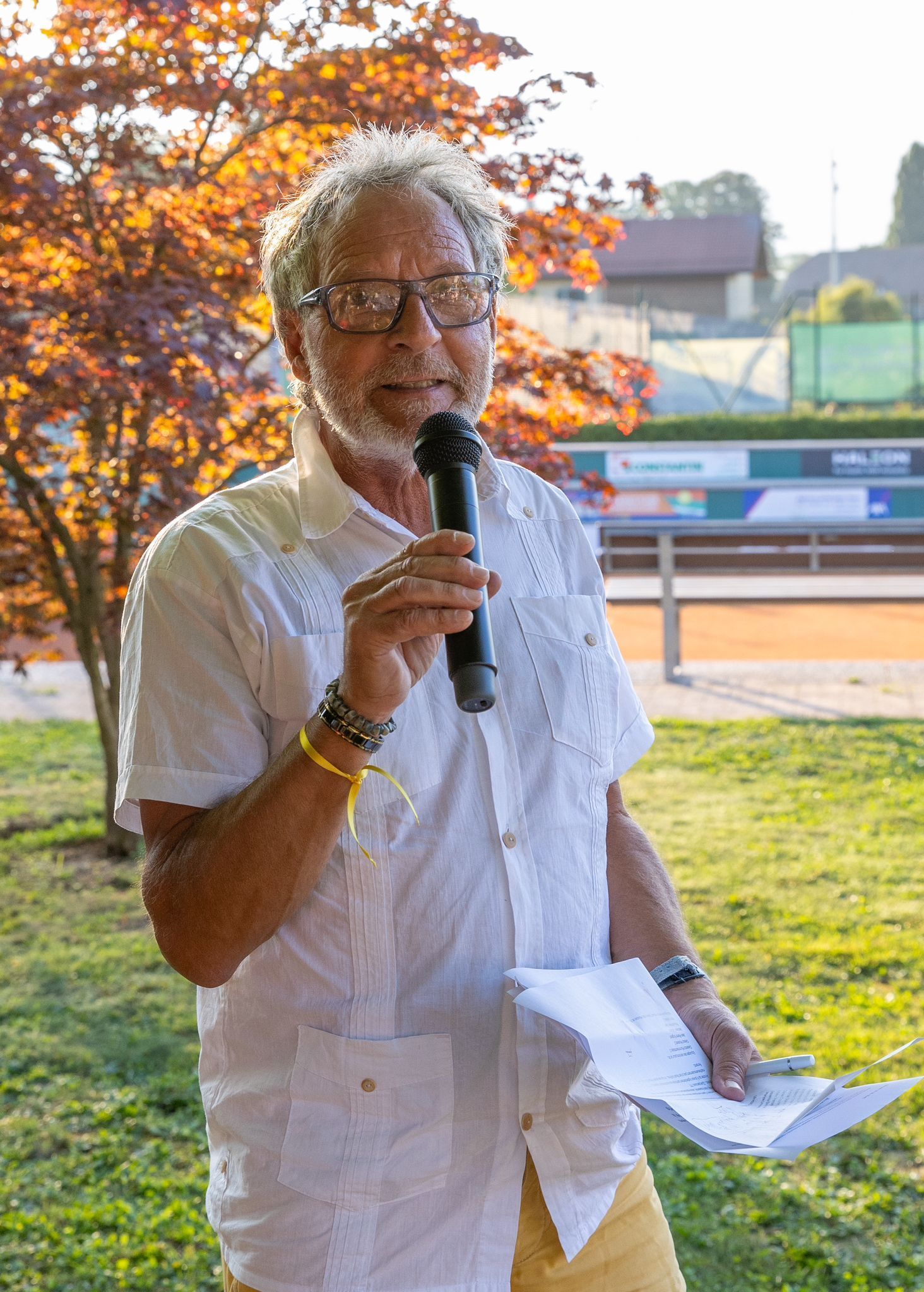 Un homme avec une barbe tient un microphone et un morceau de papier.