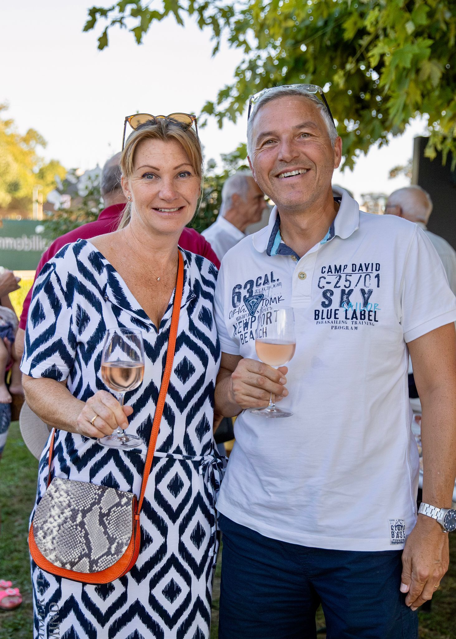 Un homme et une femme sont debout l'un à côté de l'autre, tenant des verres à vin.