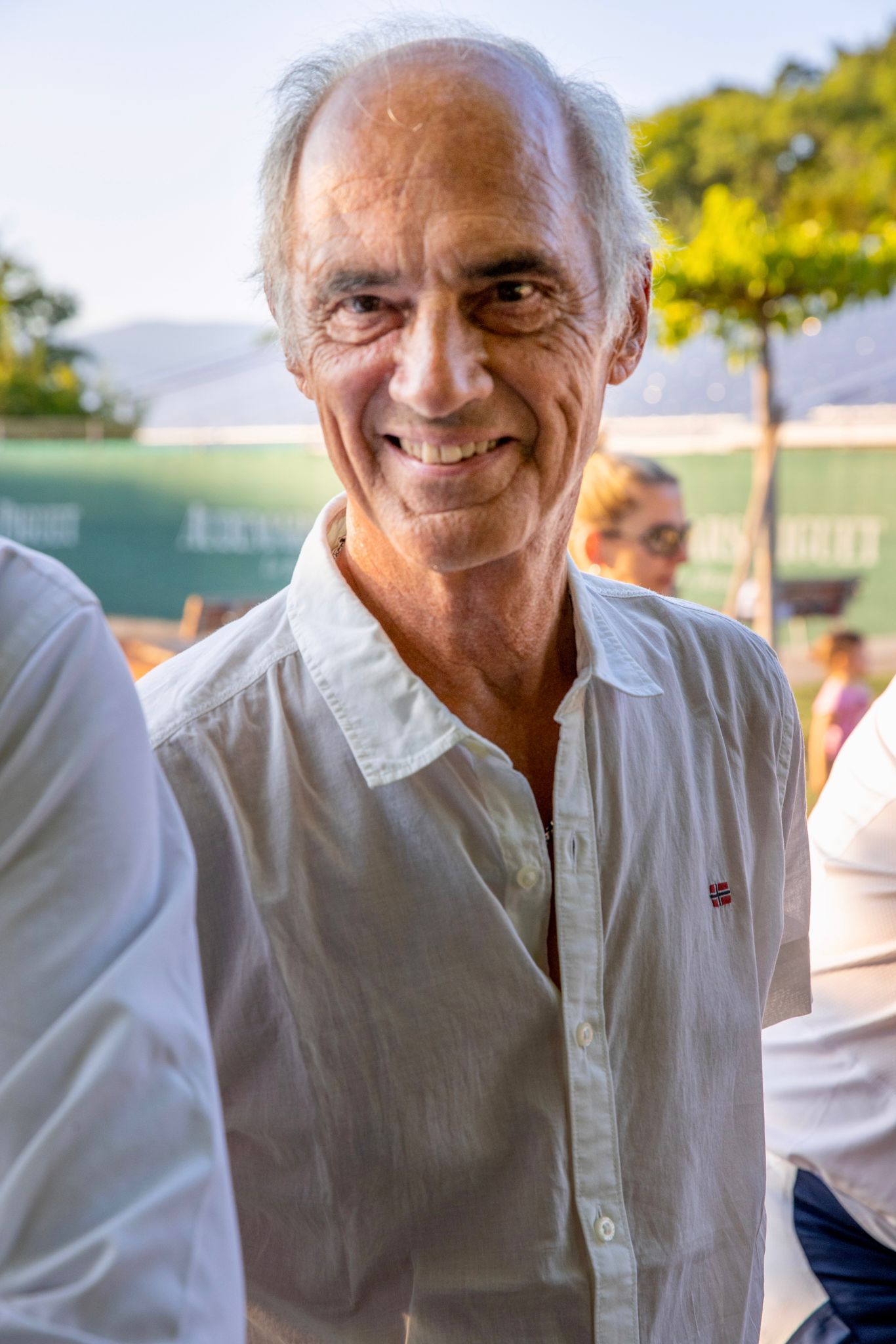 Un homme en chemise blanche sourit à la caméra.