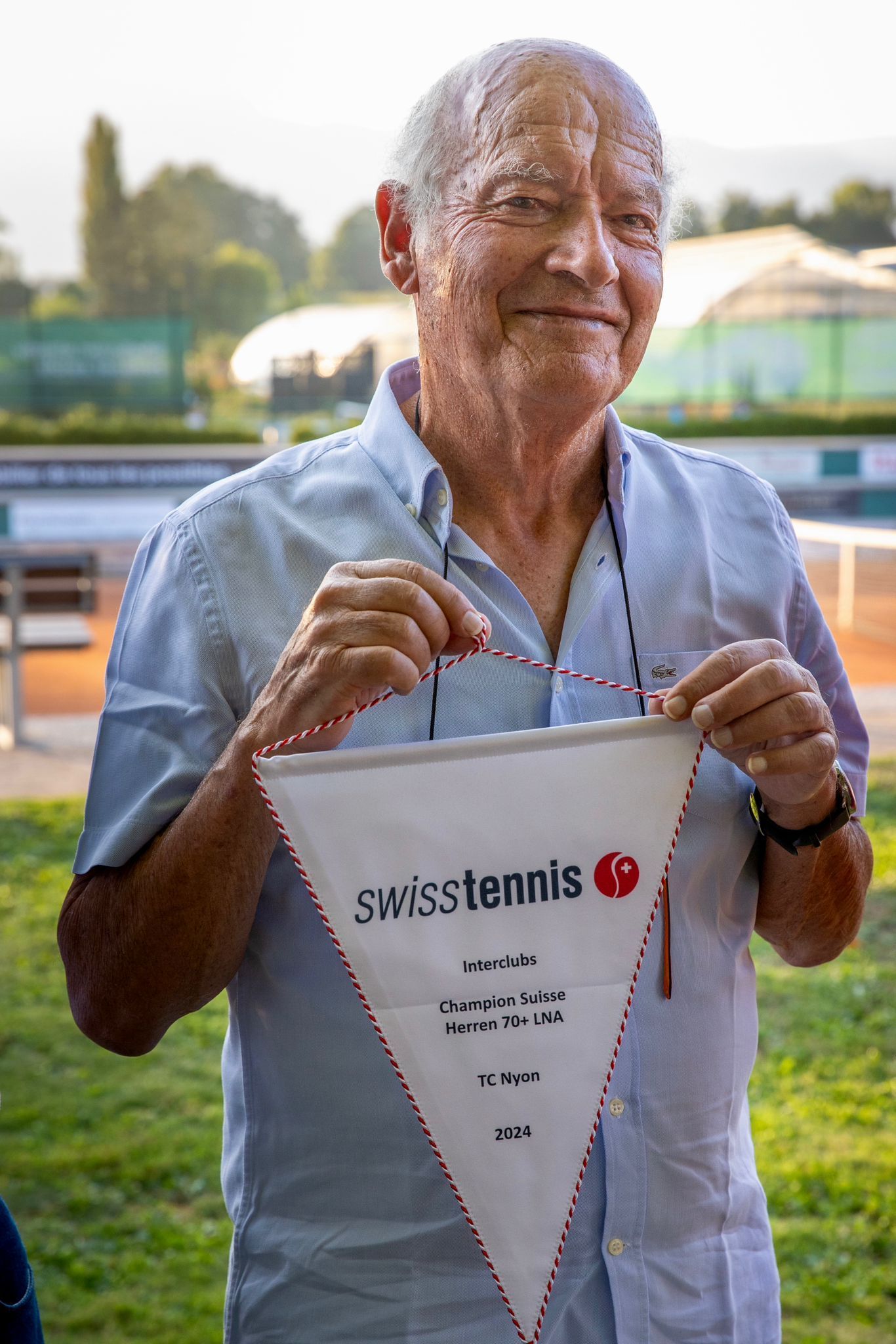 Un homme tient un drapeau de tennis suisse dans ses mains.