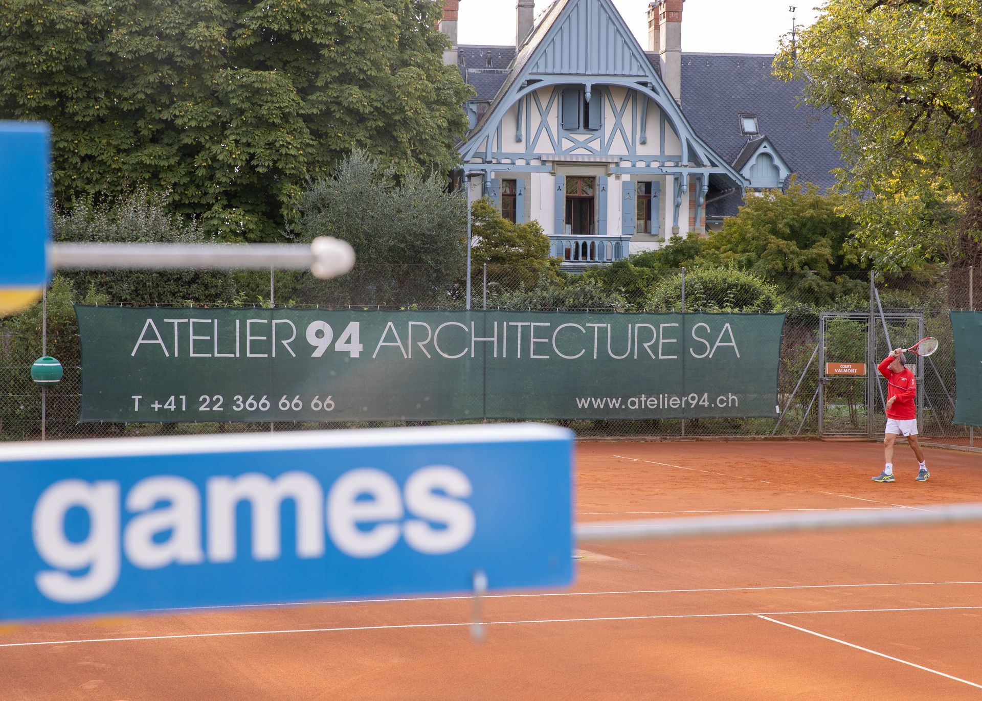 Un court de tennis avec un panneau indiquant atelier 94 architecture sa