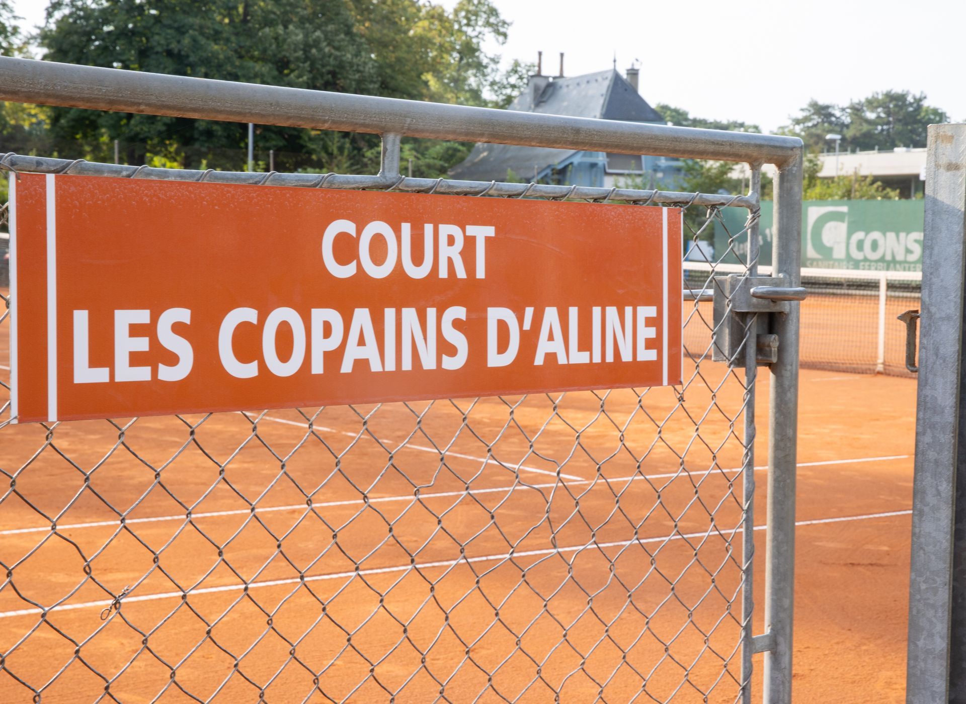 Un panneau sur une clôture grillagée dit court les copains d'aline