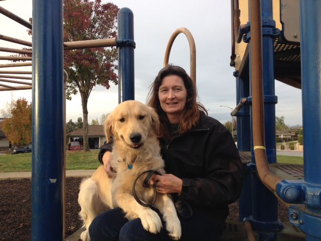 A woman holding a dog in front of a playground