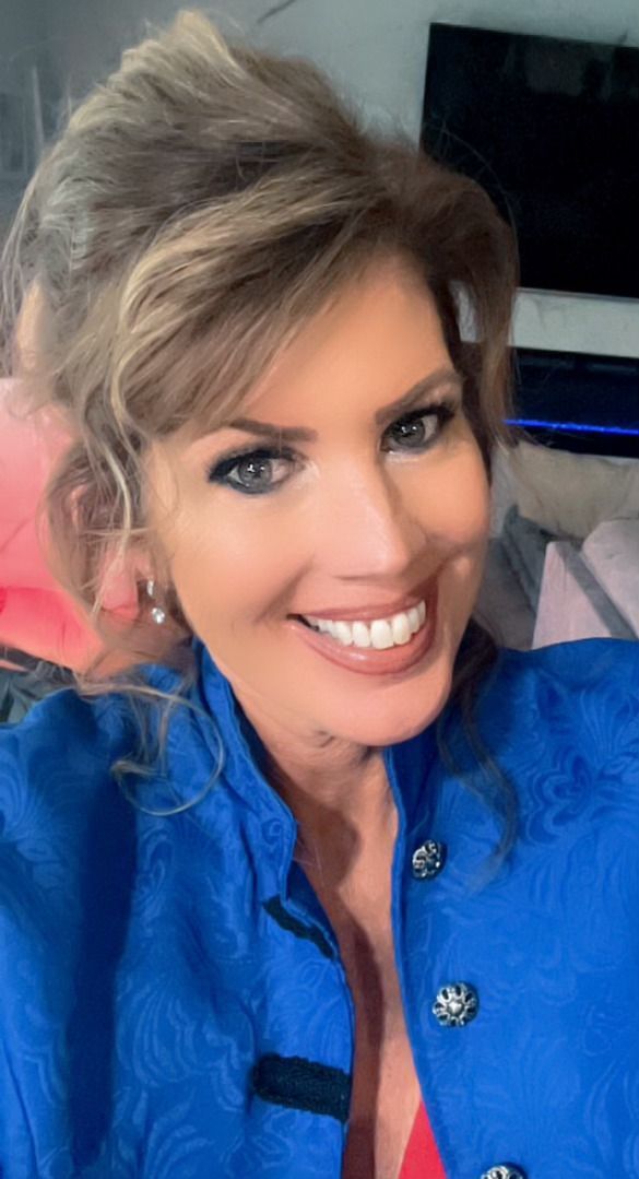 A woman in a blue jacket is smiling for the camera.