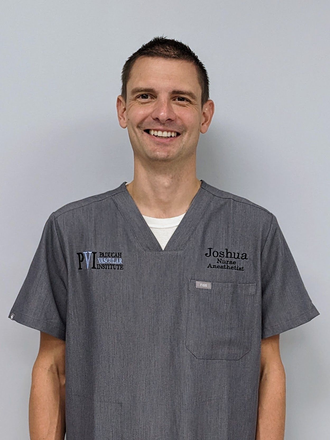Joshua Lee, CRNA, a man wearing a grey scrub with paducah vascular institute logo on it