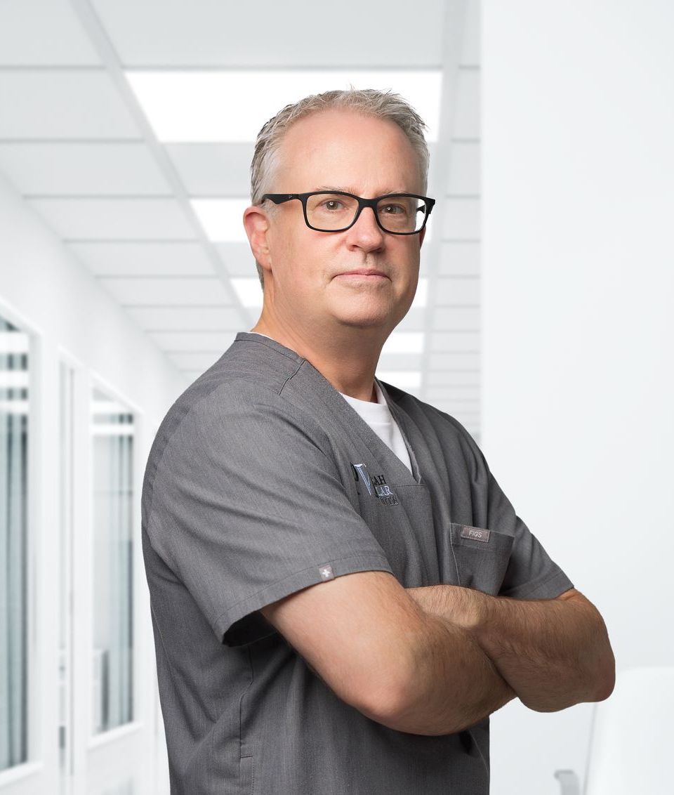 Dr. Scott Sanders, a man wearing glasses and a scrub shirt that has the paducah vascular institute logo on it