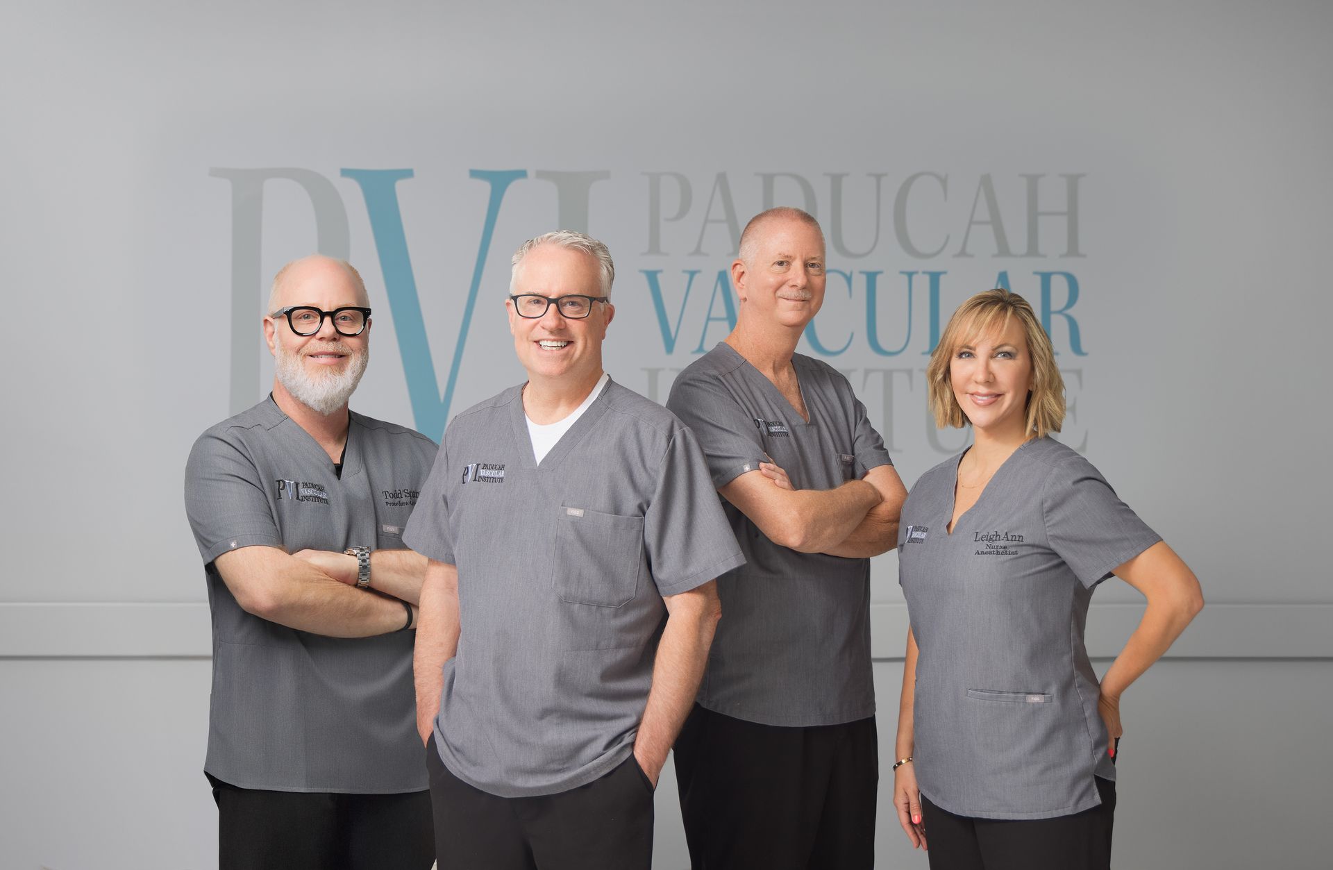 Photo of Paducah Vascular Institute staff posing in gray scrubs. Background has business logo.