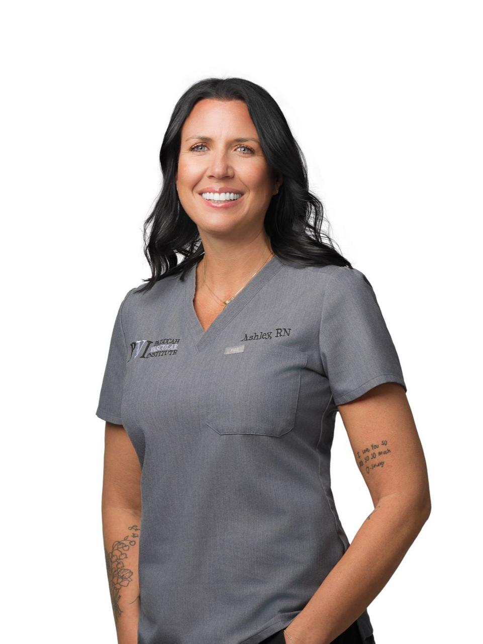 Photo of Ashley Wilson, Registered Nurse, Woman in gray scrubs smiles; arms crossed, tattoos visible.