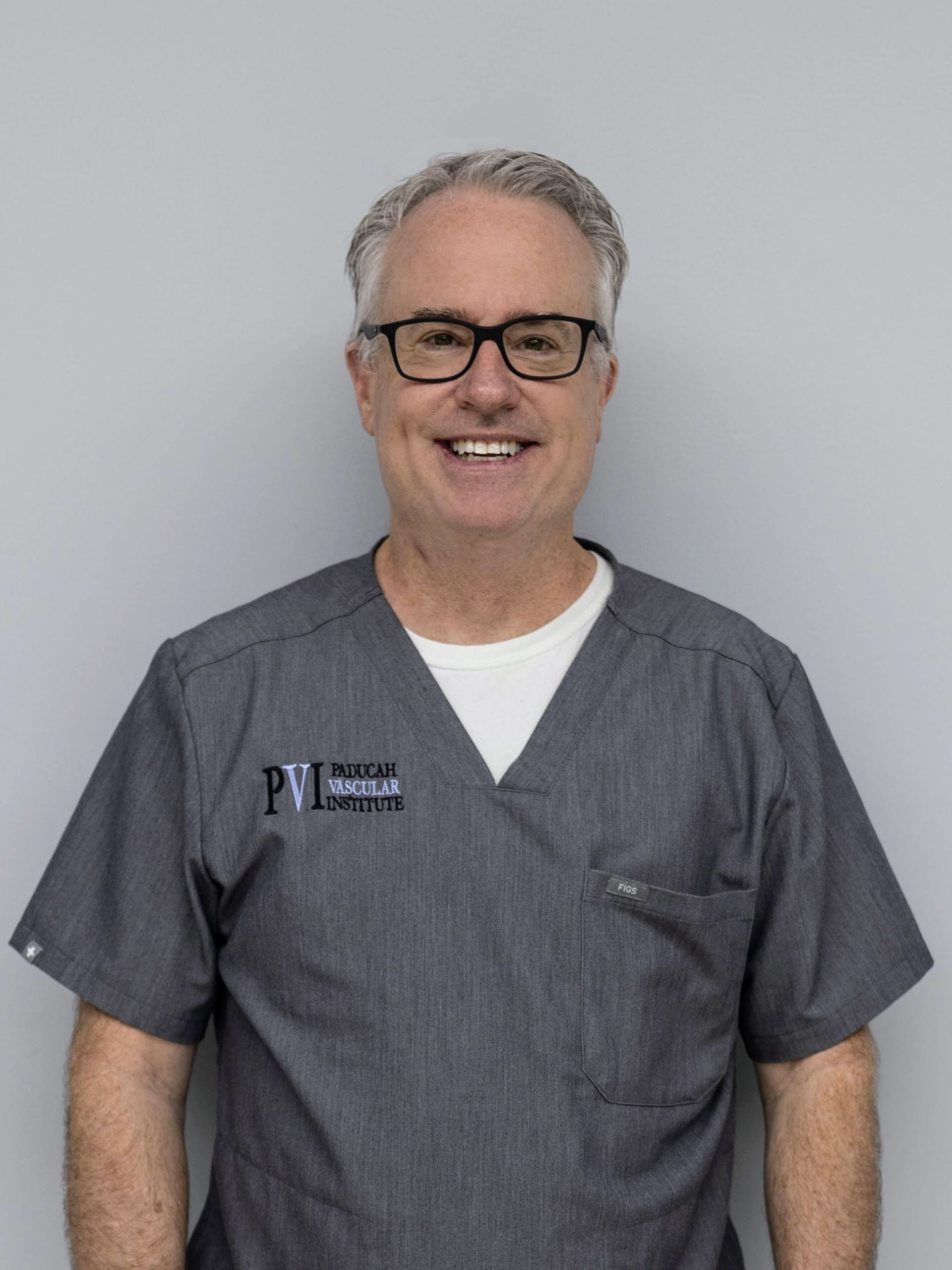 Dr. Scott Sanders, a man wearing glasses and a scrub shirt that has the paducah vascular institute logo on it