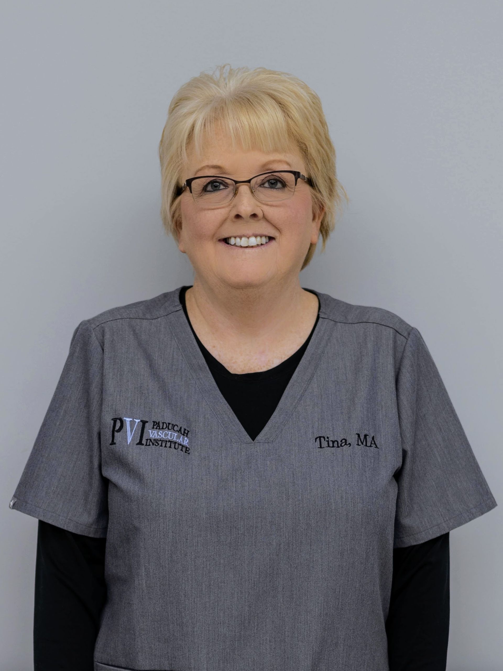 Tina Morehead, Medical Assistant, a woman wearing glasses and a scrub top that has paducah vascular institute logo on it