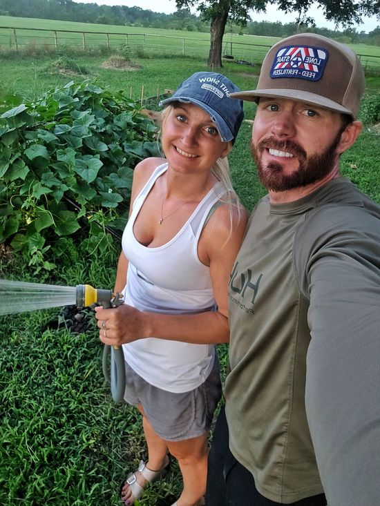 A man and a woman are standing next to each other holding a hose.