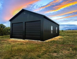 A large metal building with two black garage doors