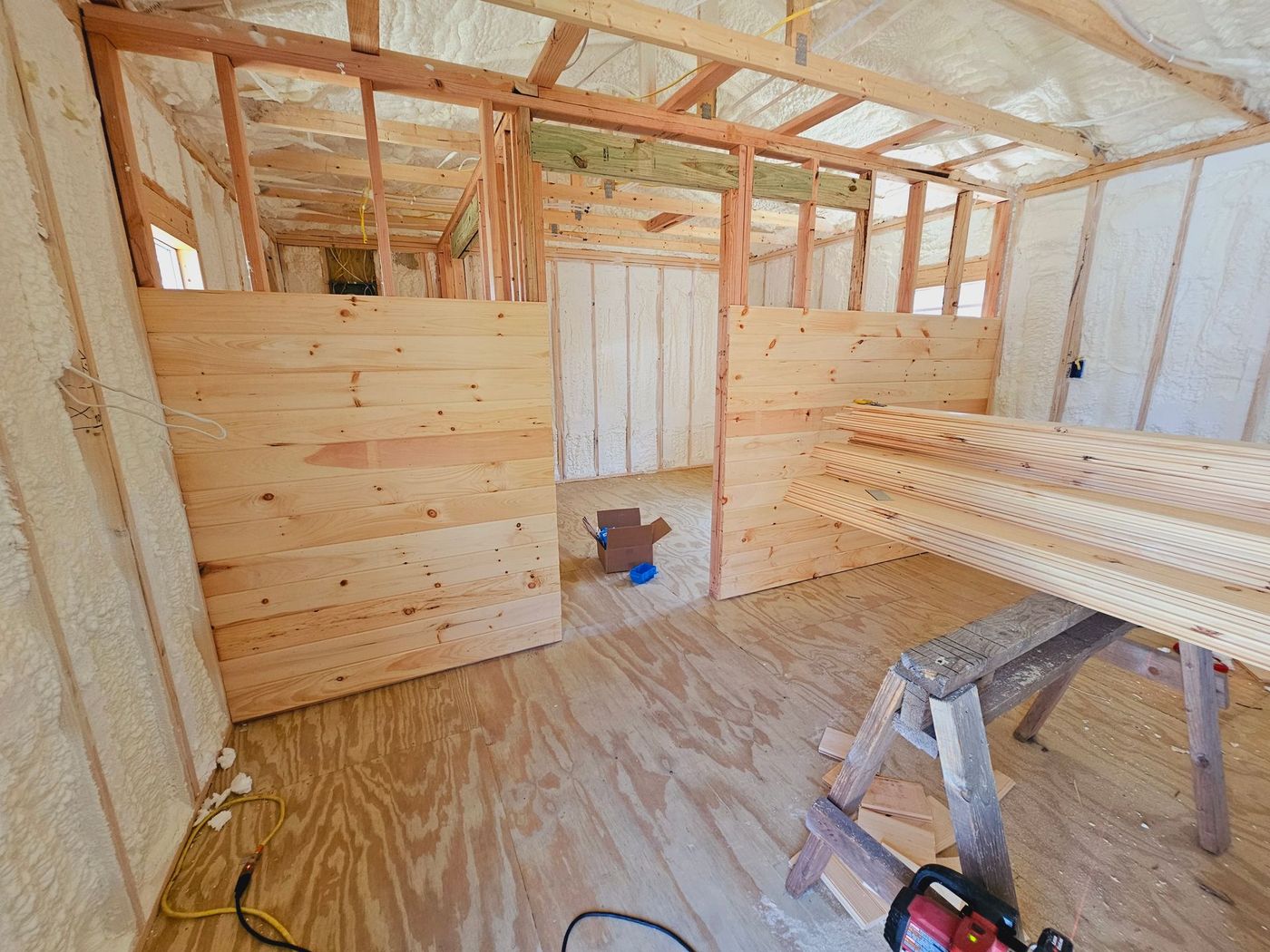 A room under construction with wooden walls and a ladder.