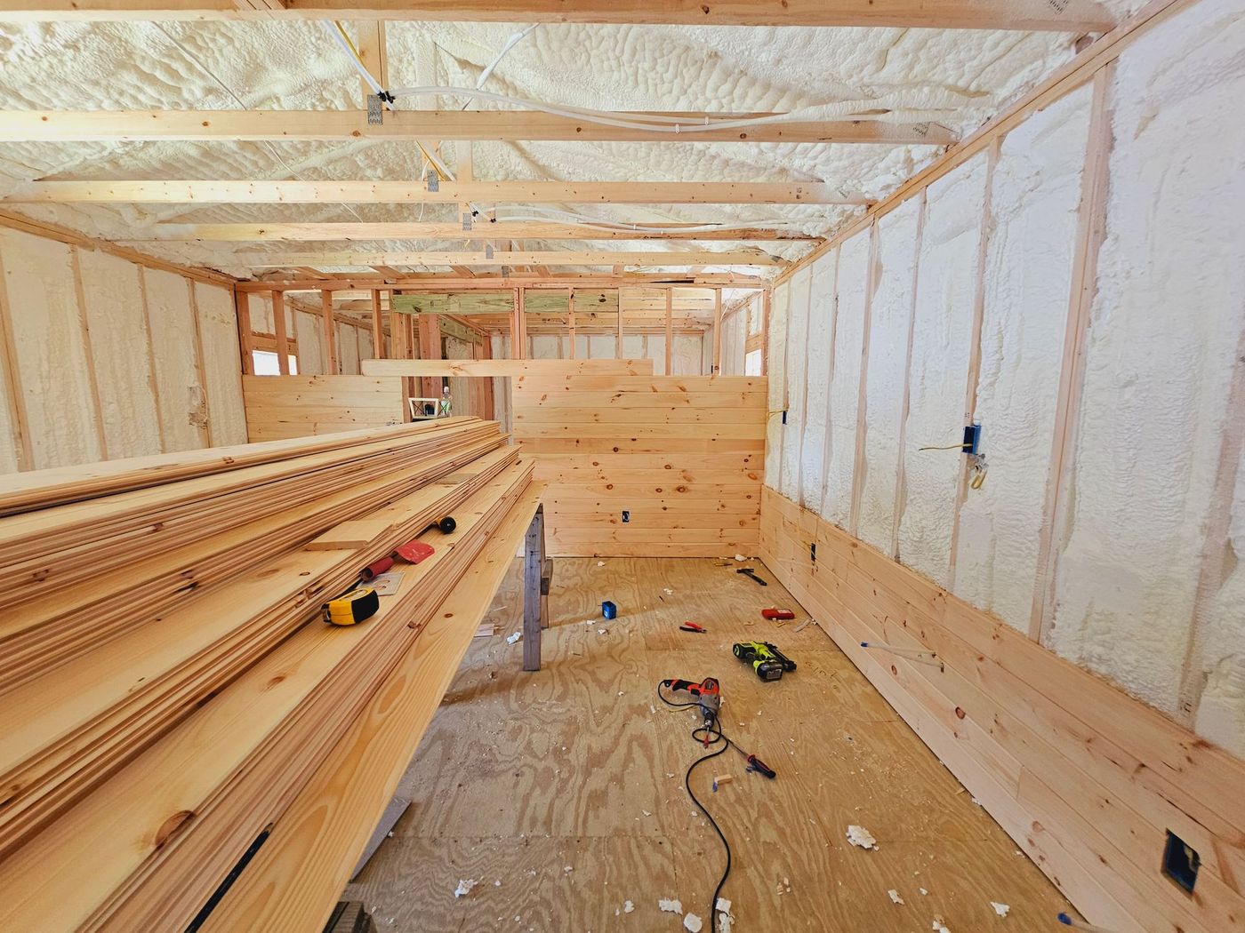 A room with a lot of wood and a drill on the floor.