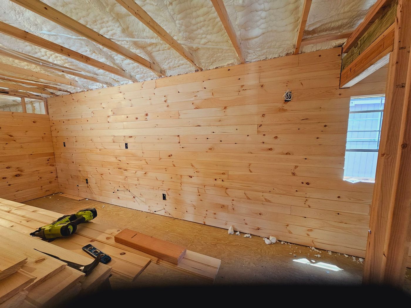 A room with wooden walls and a drill on the floor.