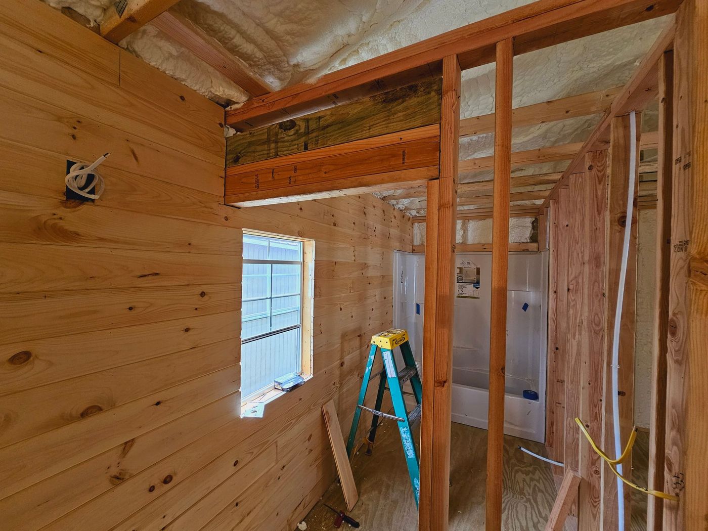 A bathroom under construction with a ladder and a window.