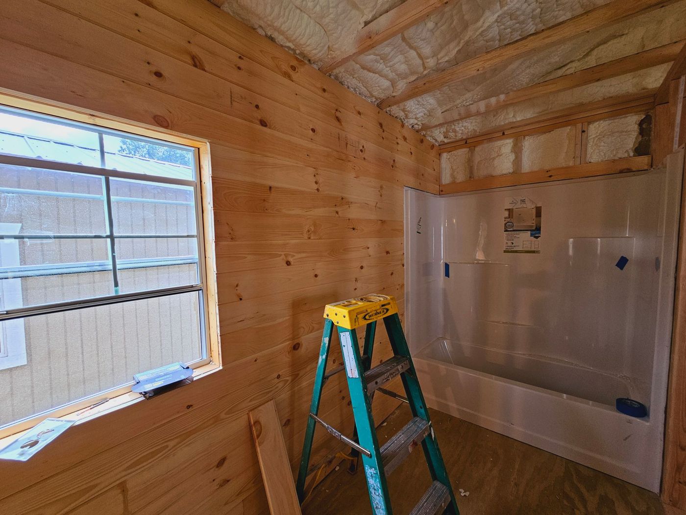 A bathroom under construction with a ladder and a bathtub.