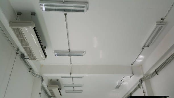 A room with a lot of lights and air conditioners on the ceiling.