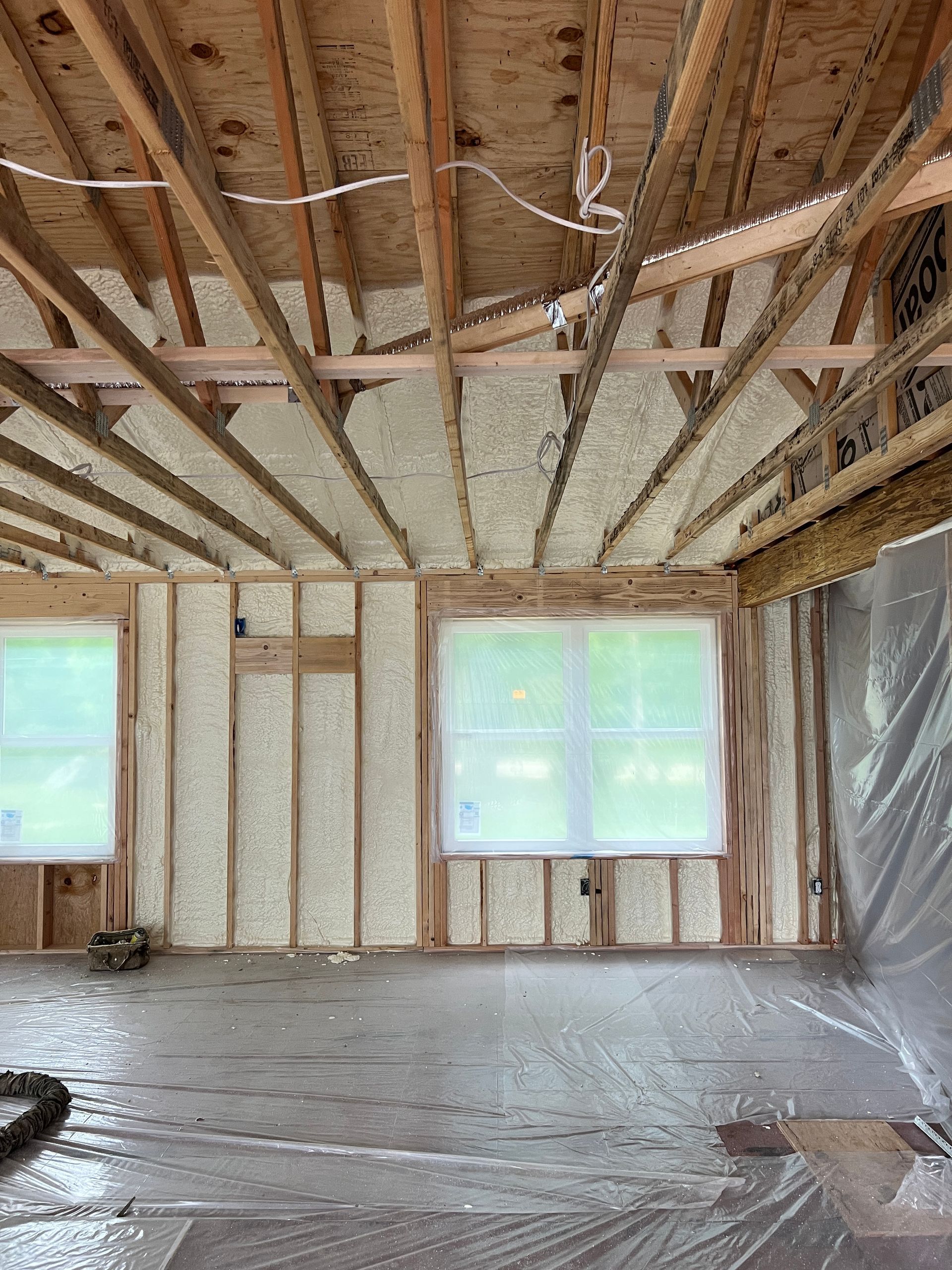 A person is spraying foam insulation on a wall.