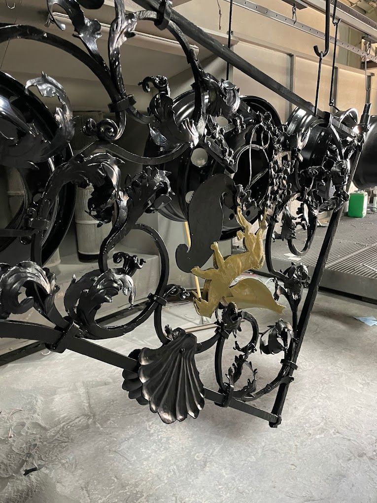 Ein schmiedeeisernes Geländer mit einem Vogel darauf wird schwarz und gold bemalt.