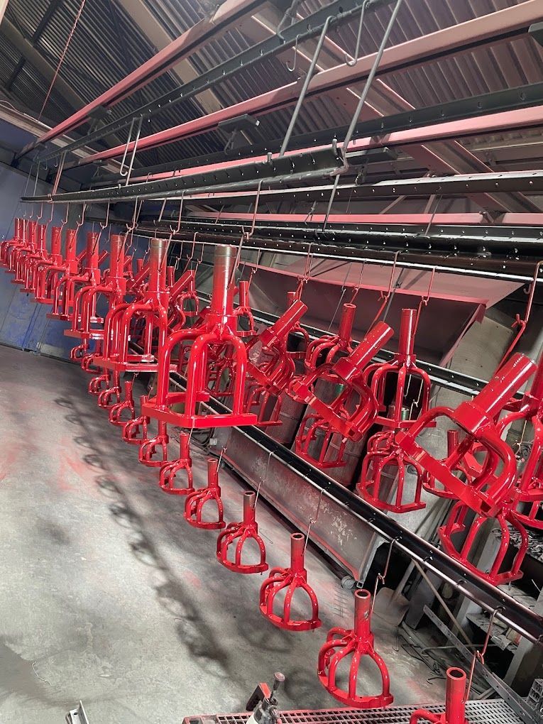 Eine Reihe roter Fahrradrahmen hängt in einer Fabrik von der Decke.