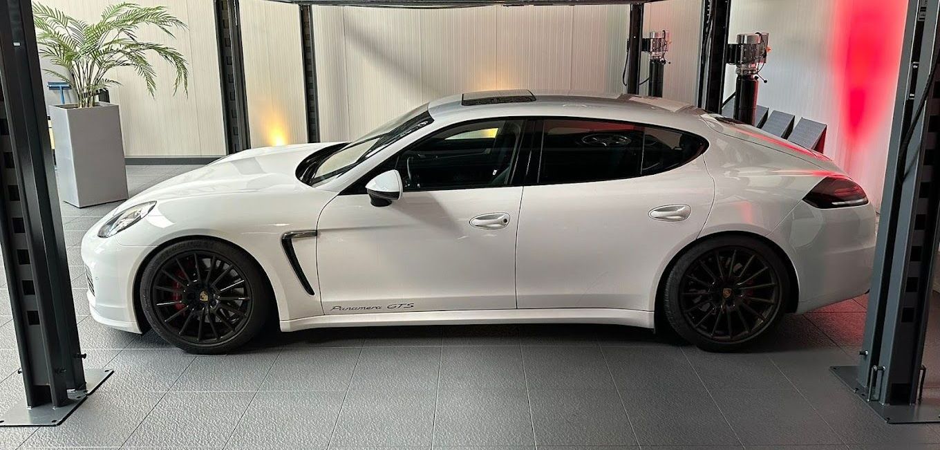 Ein weißer Porsche Panamera steht in einer Garage.