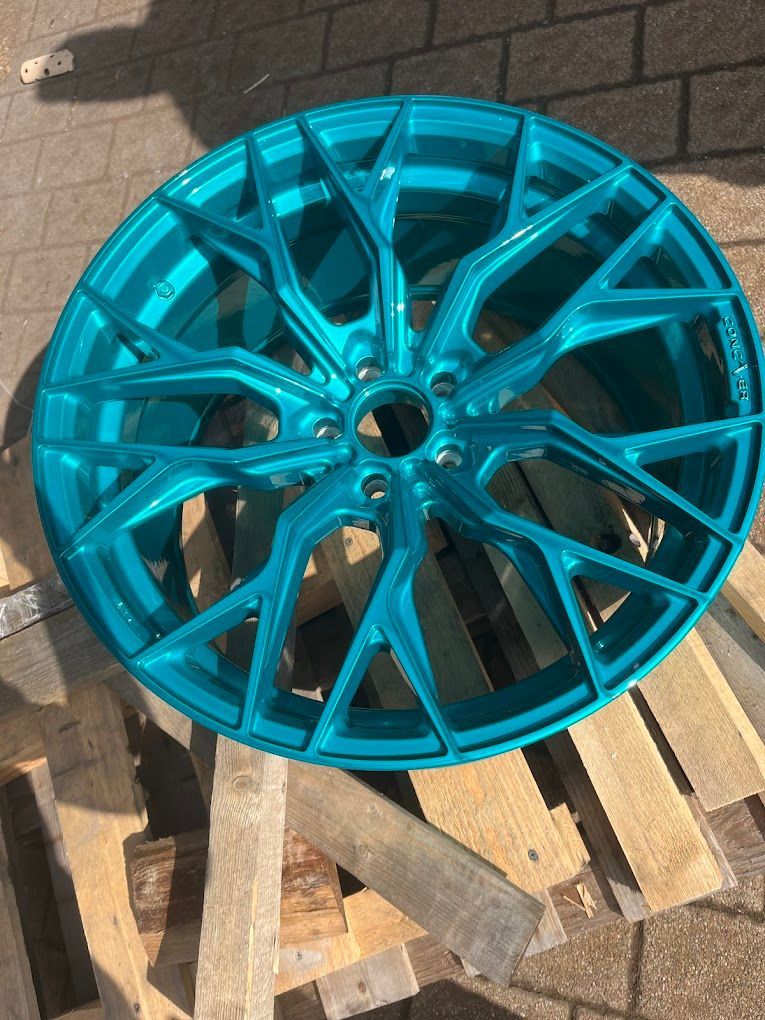 Auf einer Holzpalette liegt eine blaue Felge.