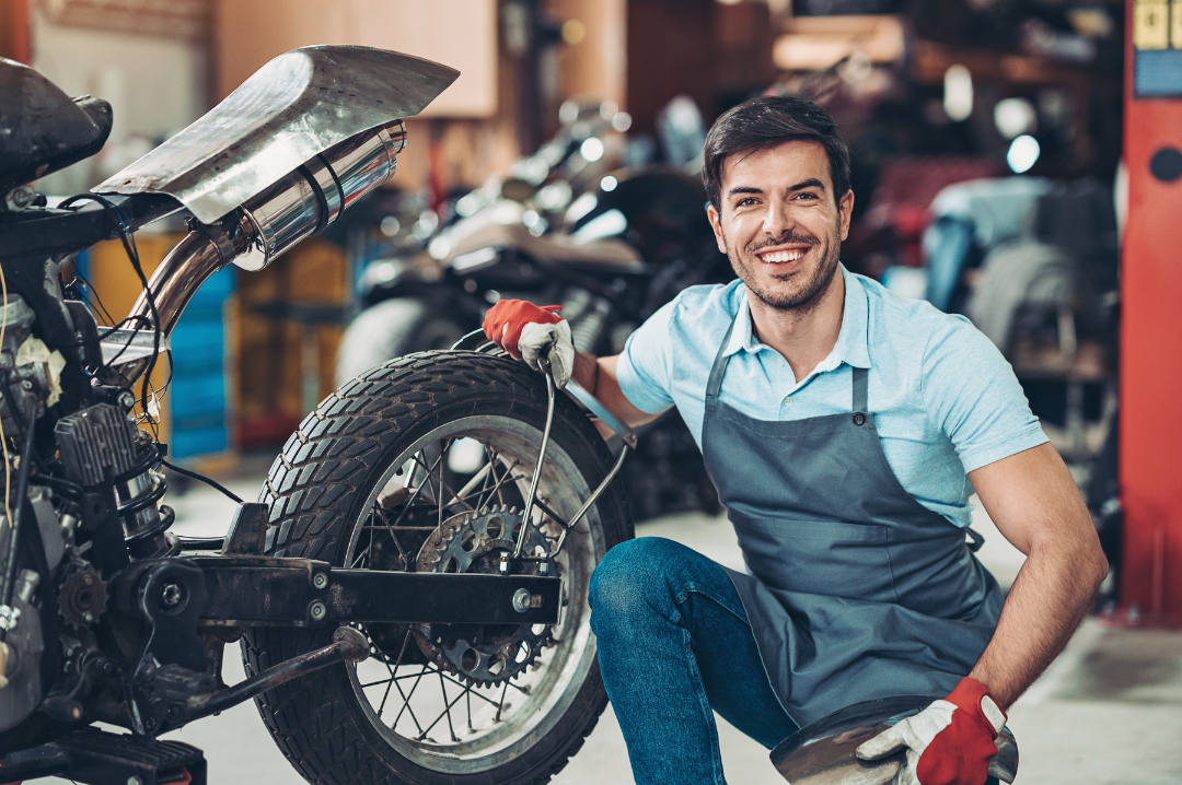 Ein Mann sitzt neben einem Motorrad in einer Garage.
