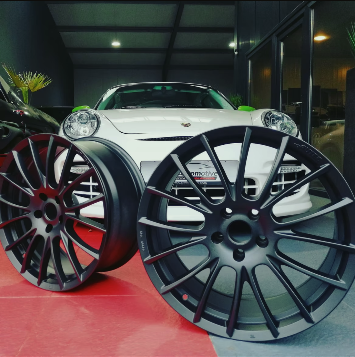 Ein weißes Auto ist neben einem Paar schwarzer Felgen geparkt