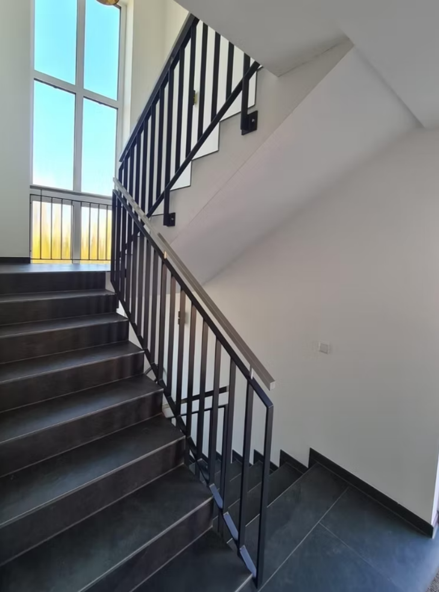 Eine Treppe mit einem Metallgeländer und einem Fenster